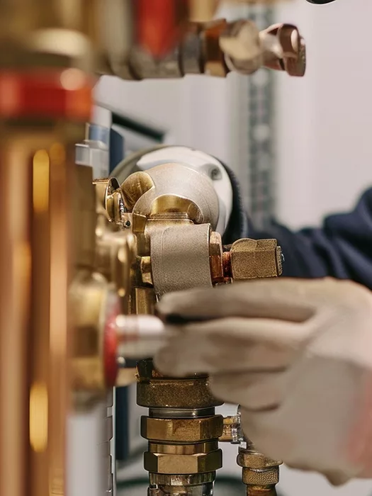 Professional plumber repairing a tank water heater in a commercial boiler room