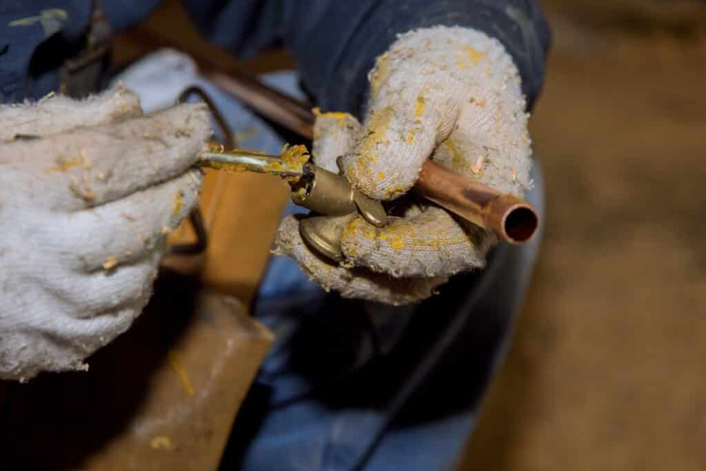 hands-working-on-copper-pipe-