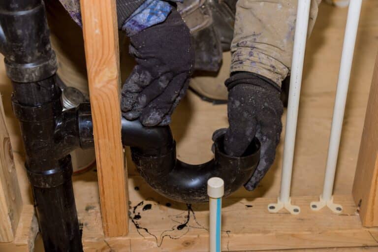 plumber-holding-pipe-fitting-component-in-a-home